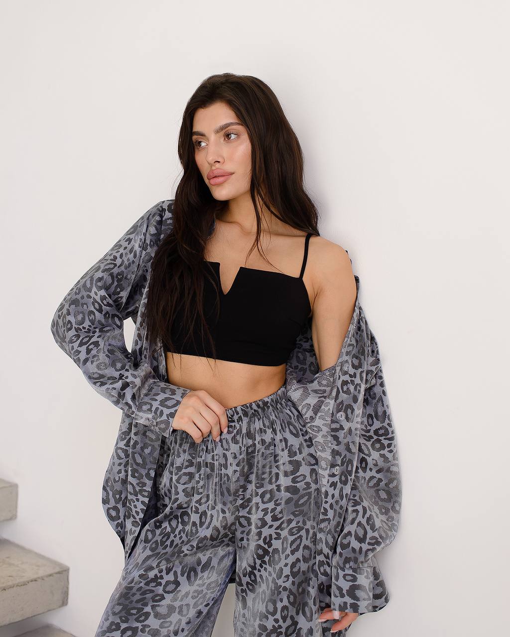 Woman wearing a black leopard print outfit against a white background