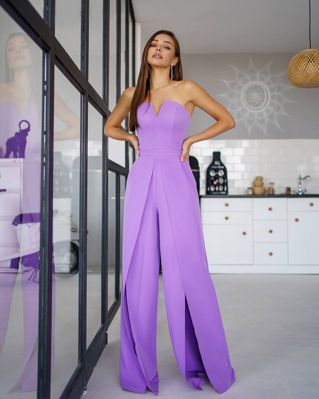 Woman wearing a purple strapless jumpsuit in a modern kitchen setting