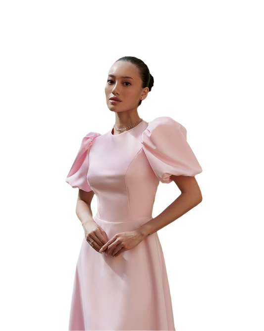 Woman wearing a pink dress with puffed sleeves on a white background
