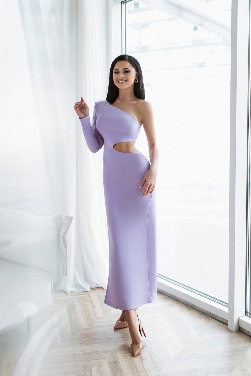 Woman wearing a one-shoulder lavender dress with cut-out design in a bright room.