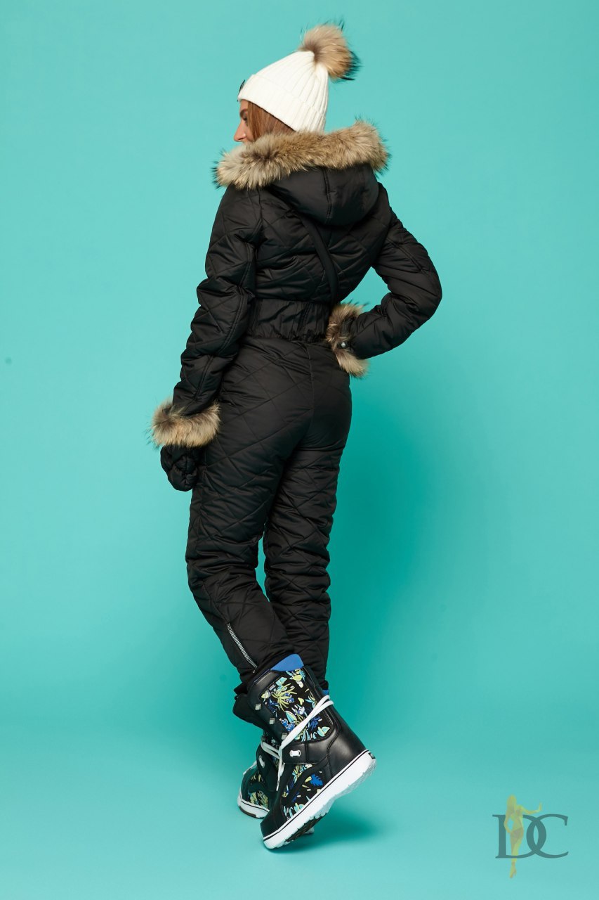 Person wearing a black winter outfit with fur trim on a teal background