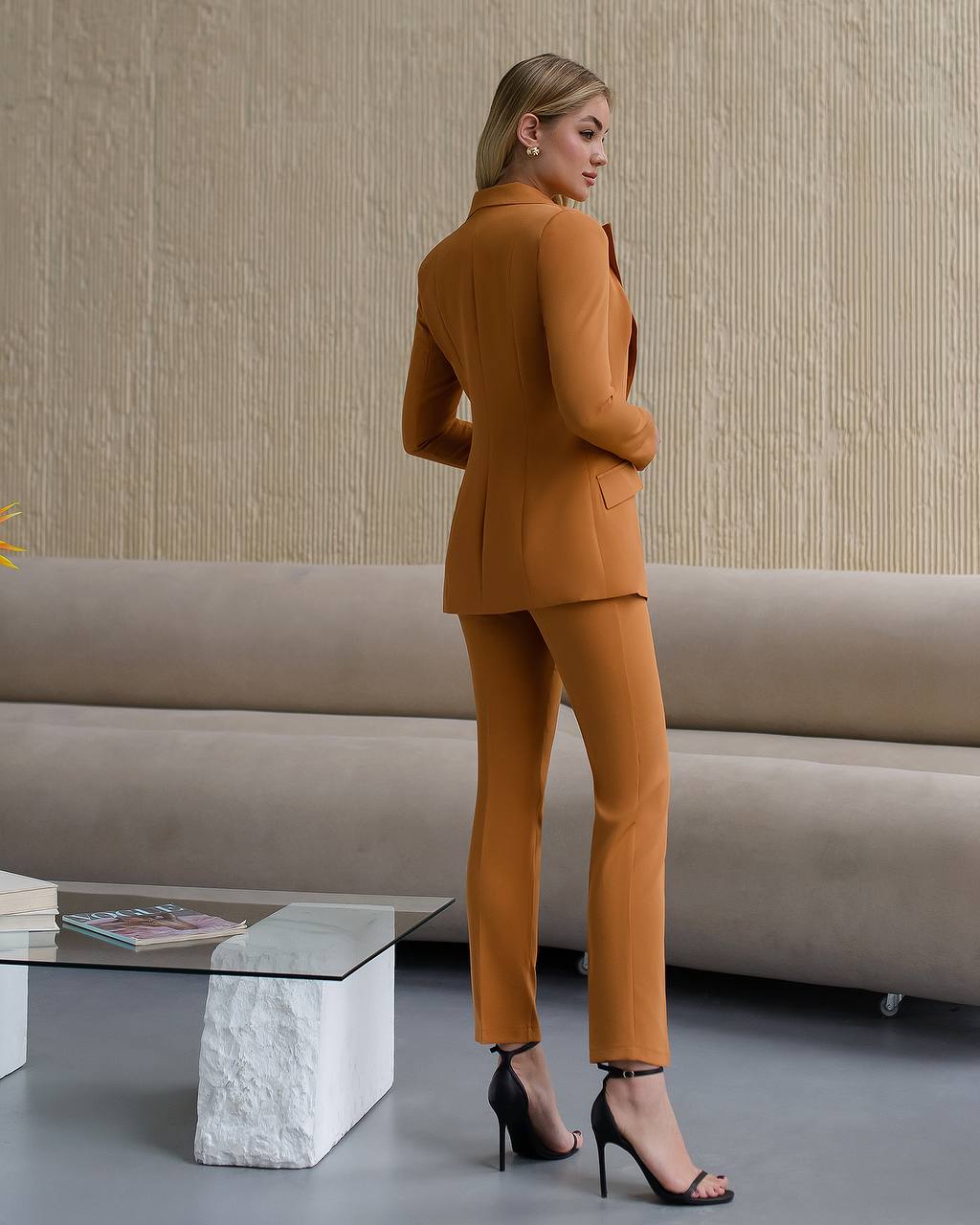 Woman in a mustard yellow suit standing in a modern living room.
