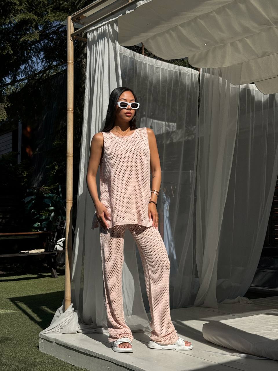Woman in a pink outfit standing on a platform with a white curtain in the background