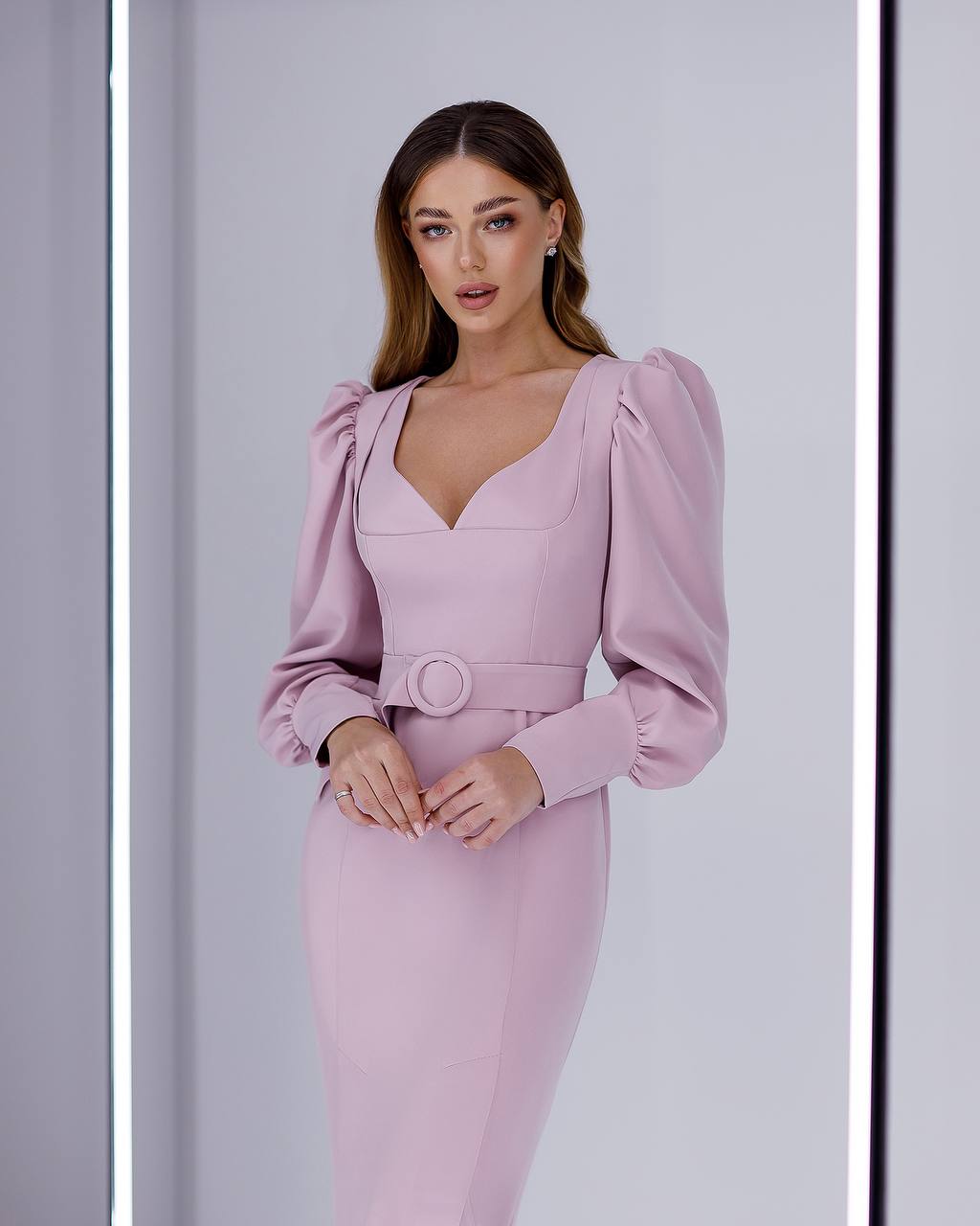 Woman wearing a pink dress with puffed sleeves against a light gray background