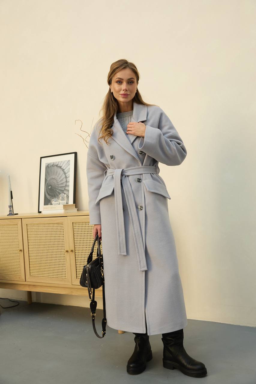 Woman wearing a long gray coat in an indoor setting