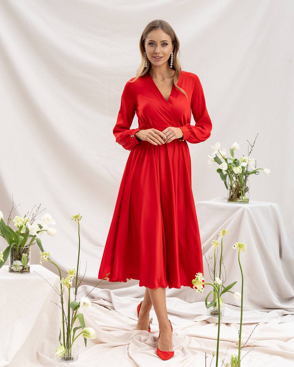 Woman wearing a red dress standing in a decorated room with flowers.