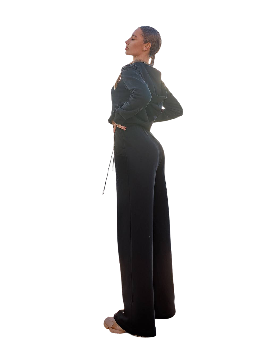 Woman wearing a dark green top and black pants on a white background