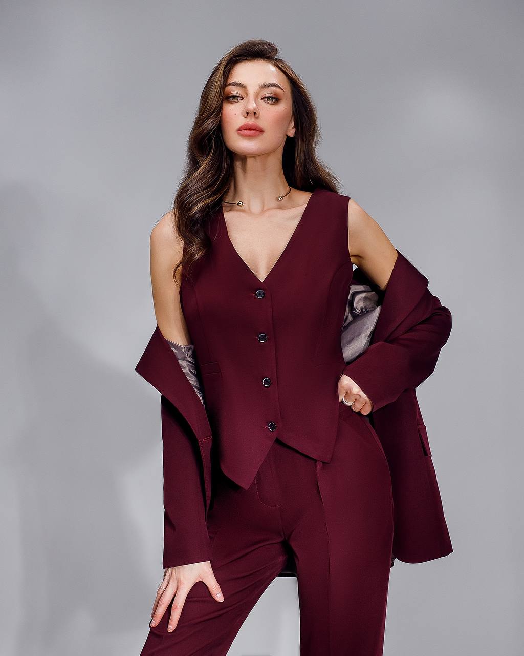Woman wearing a burgundy suit against a gray background