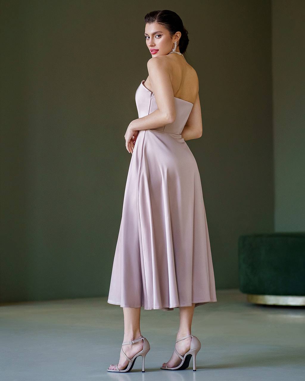 Woman wearing a light pink dress with a green background