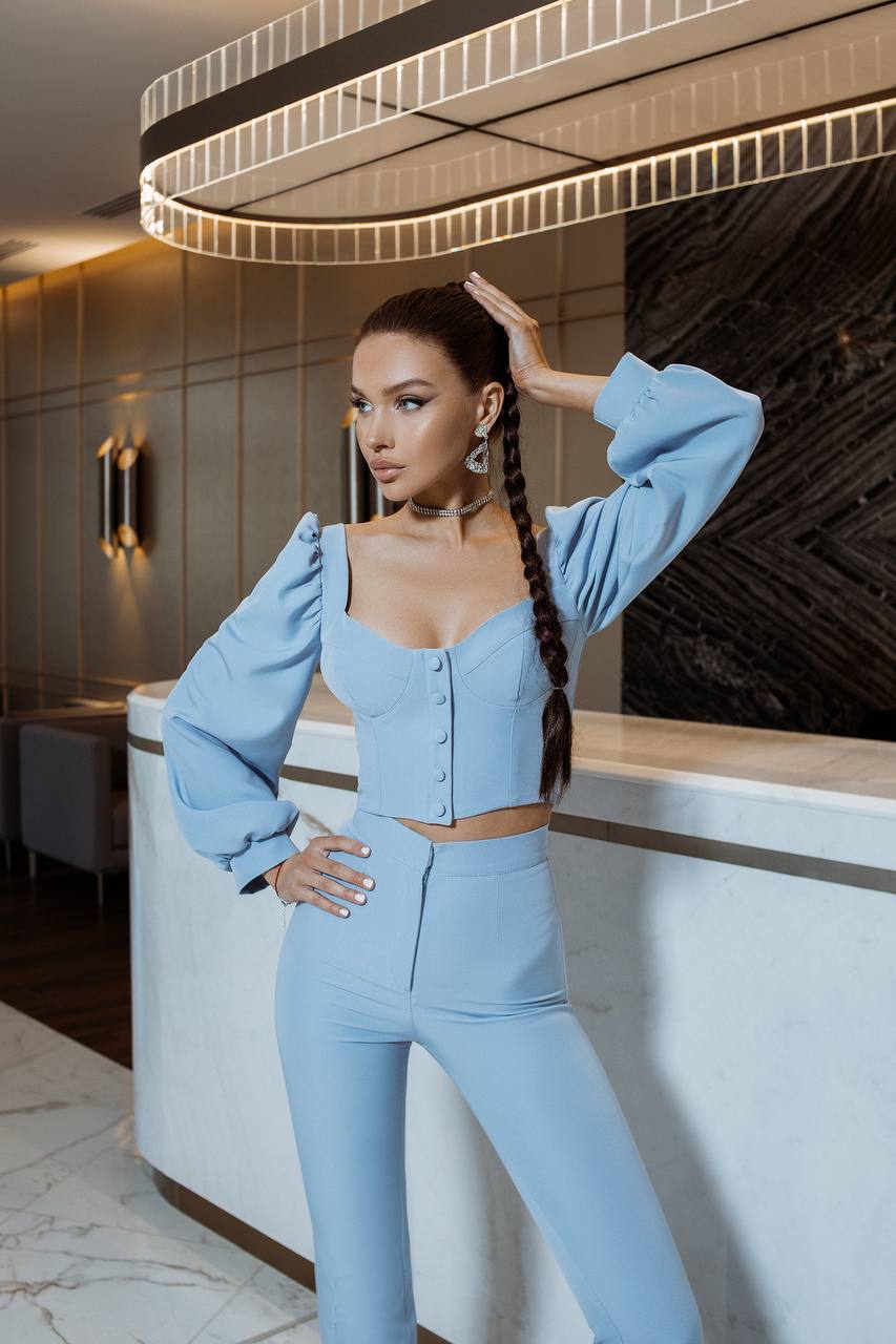 Woman in a light blue outfit posing in an elegant interior setting