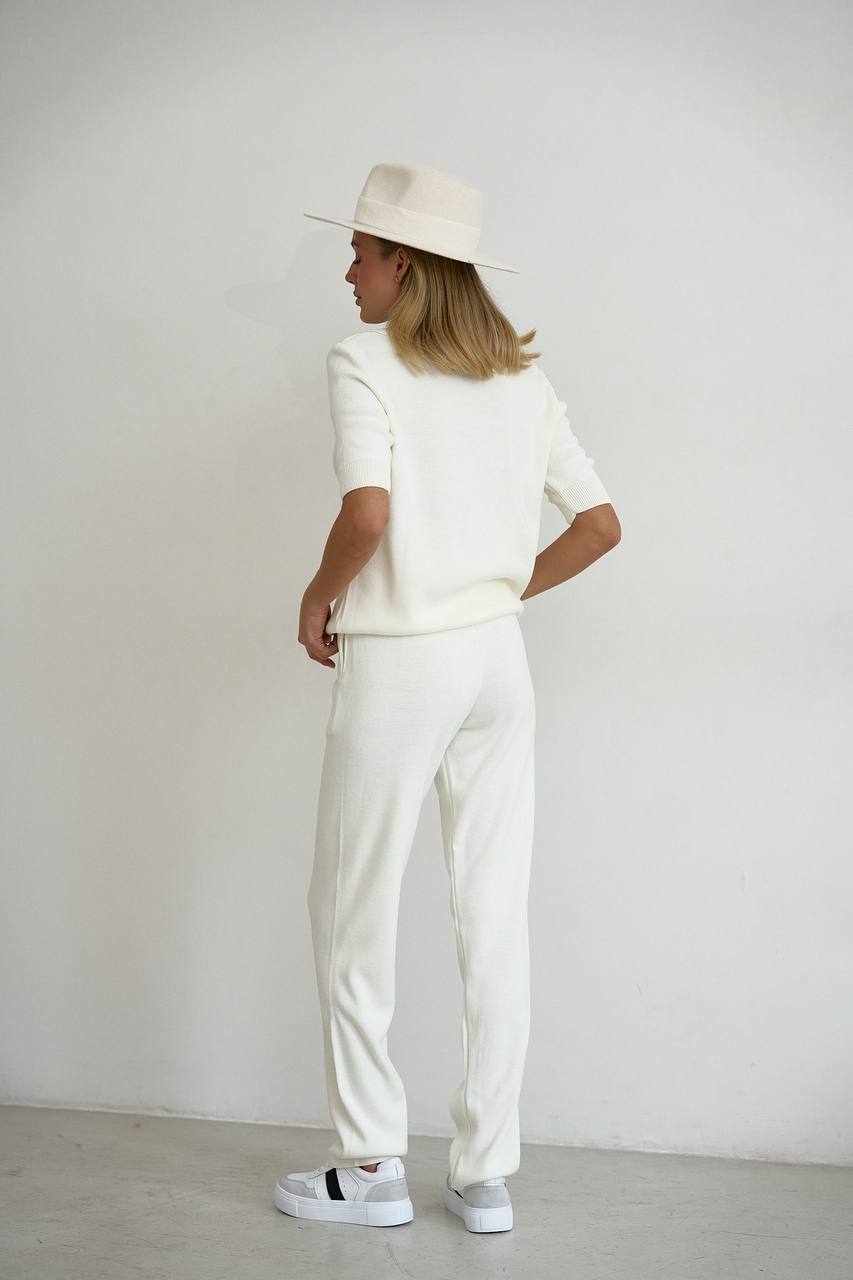 Person wearing a white outfit with a hat against a plain background