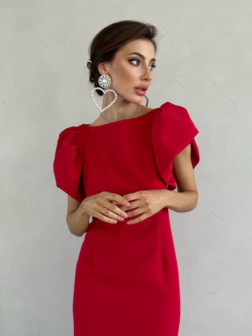 Woman wearing a red dress with puffed sleeves against a plain background