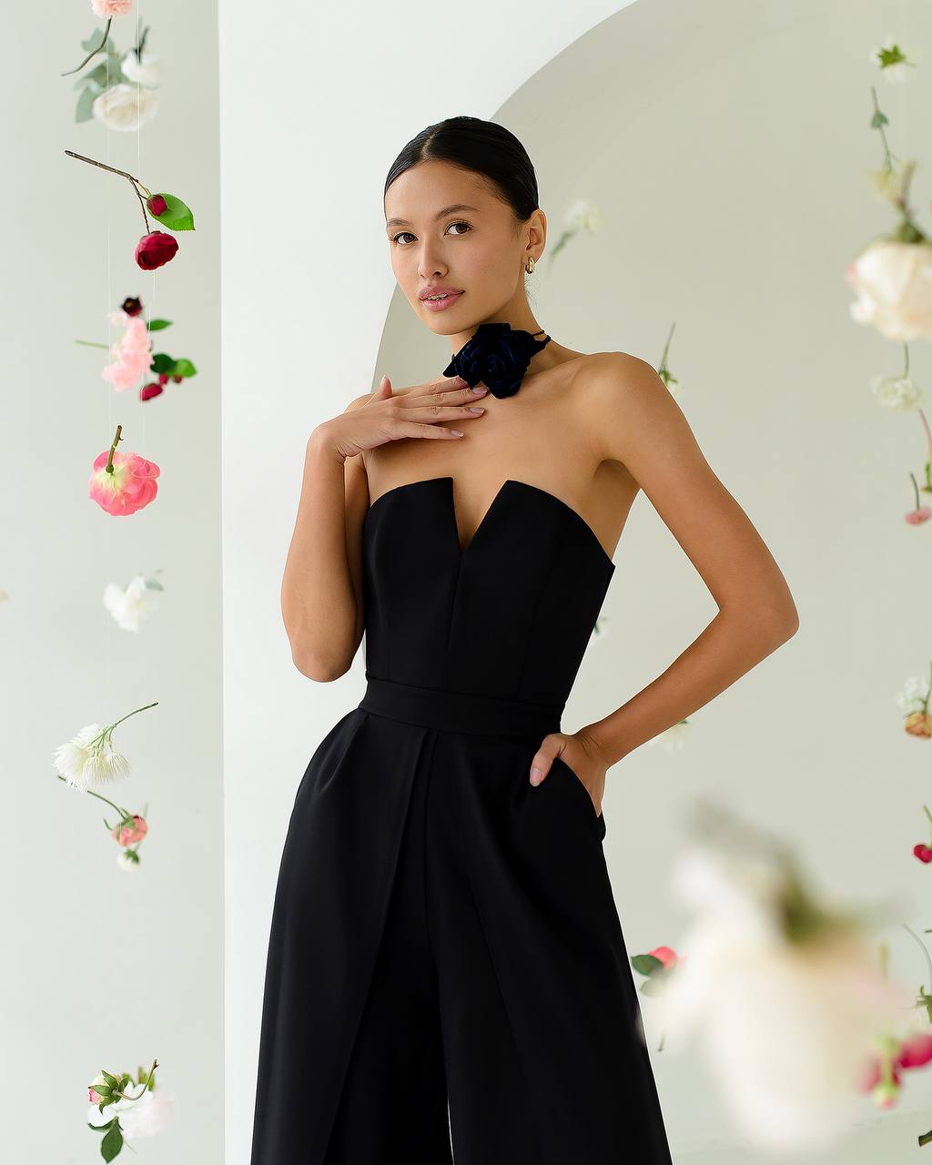 Woman wearing a black strapless dress with floral decorations in the background