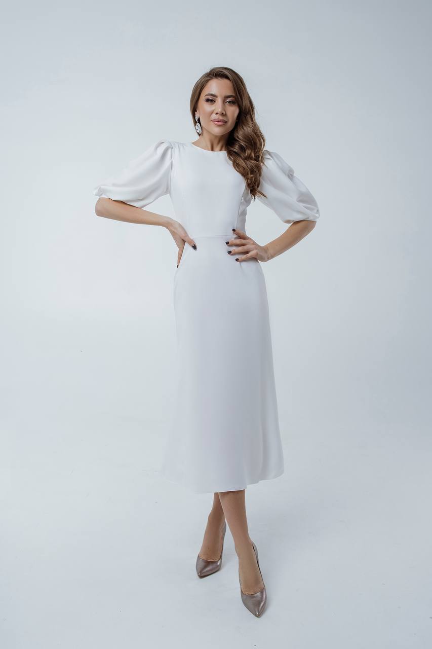 Woman wearing a white dress with puffed sleeves on a light gray background