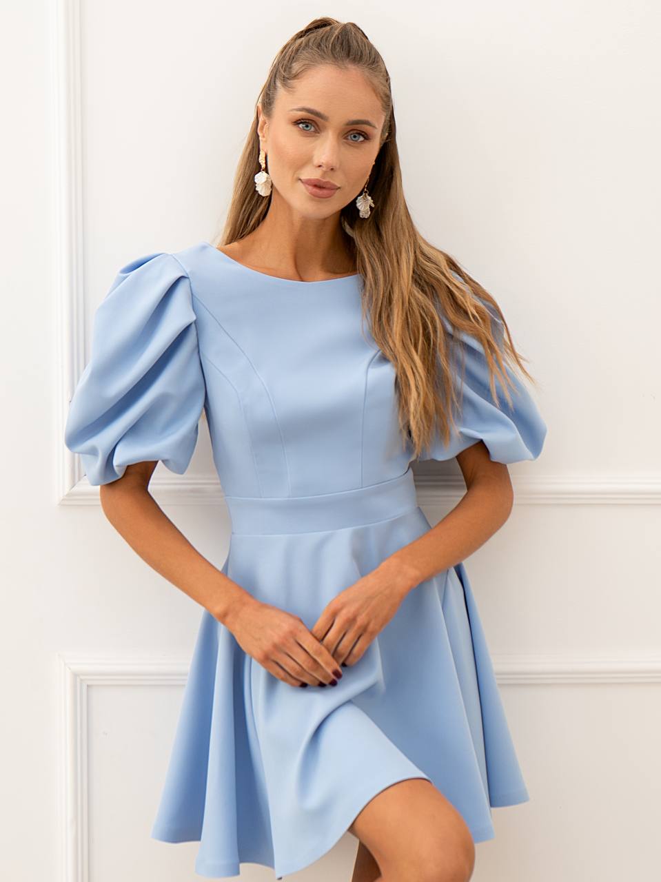 Woman wearing a light blue dress with puffed sleeves against a white background