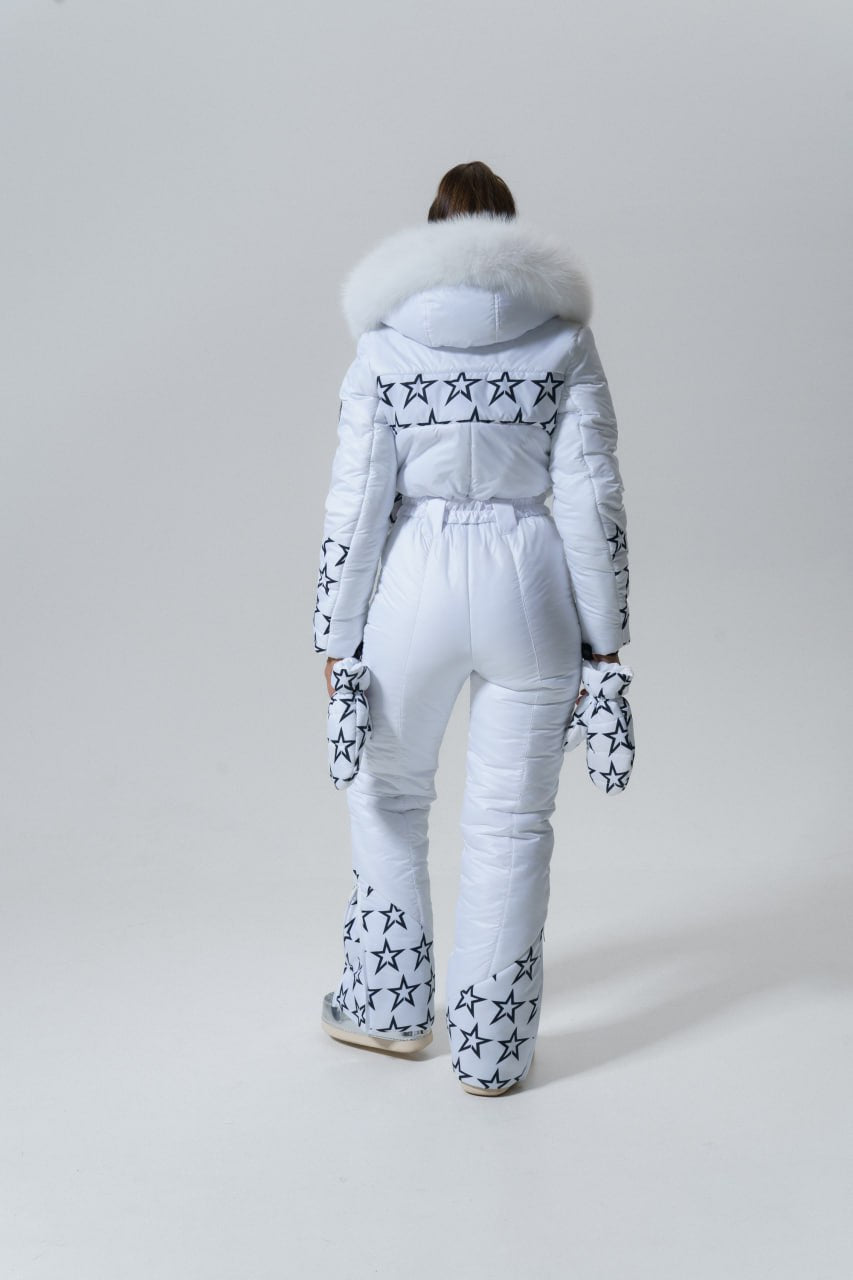 Person wearing a white snowsuit with star patterns and fur-lined hood on a light gray background