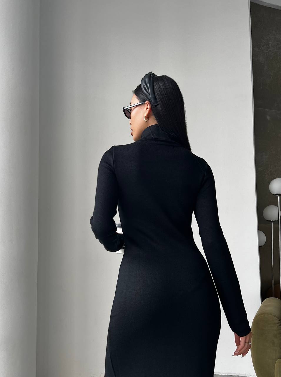 Woman wearing a black dress and headscarf in an indoor setting