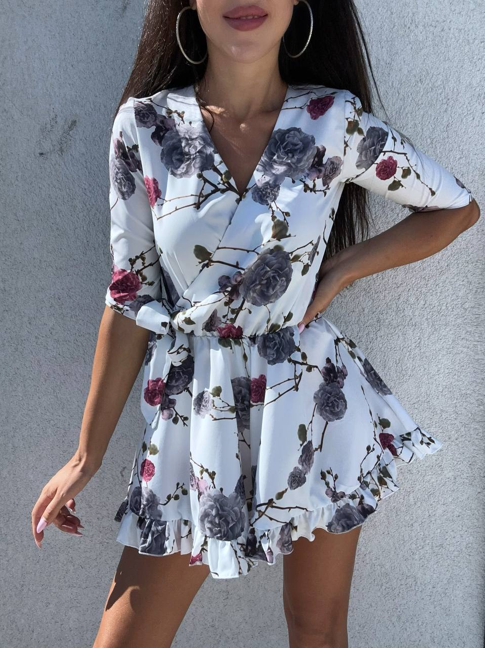 Woman wearing a floral dress against a gray wall