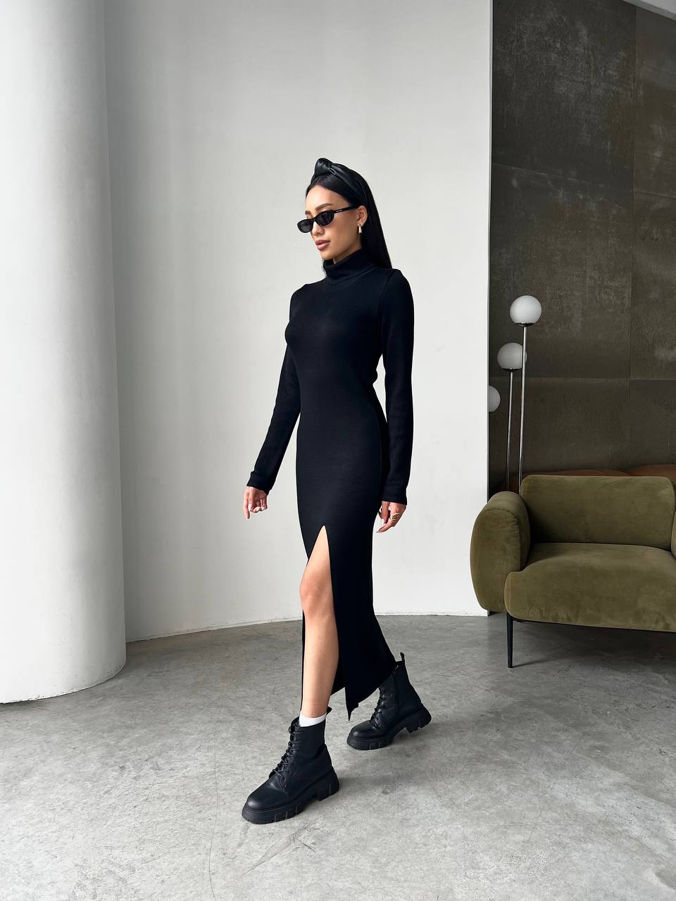 Person wearing a black outfit with a high slit in a modern room.