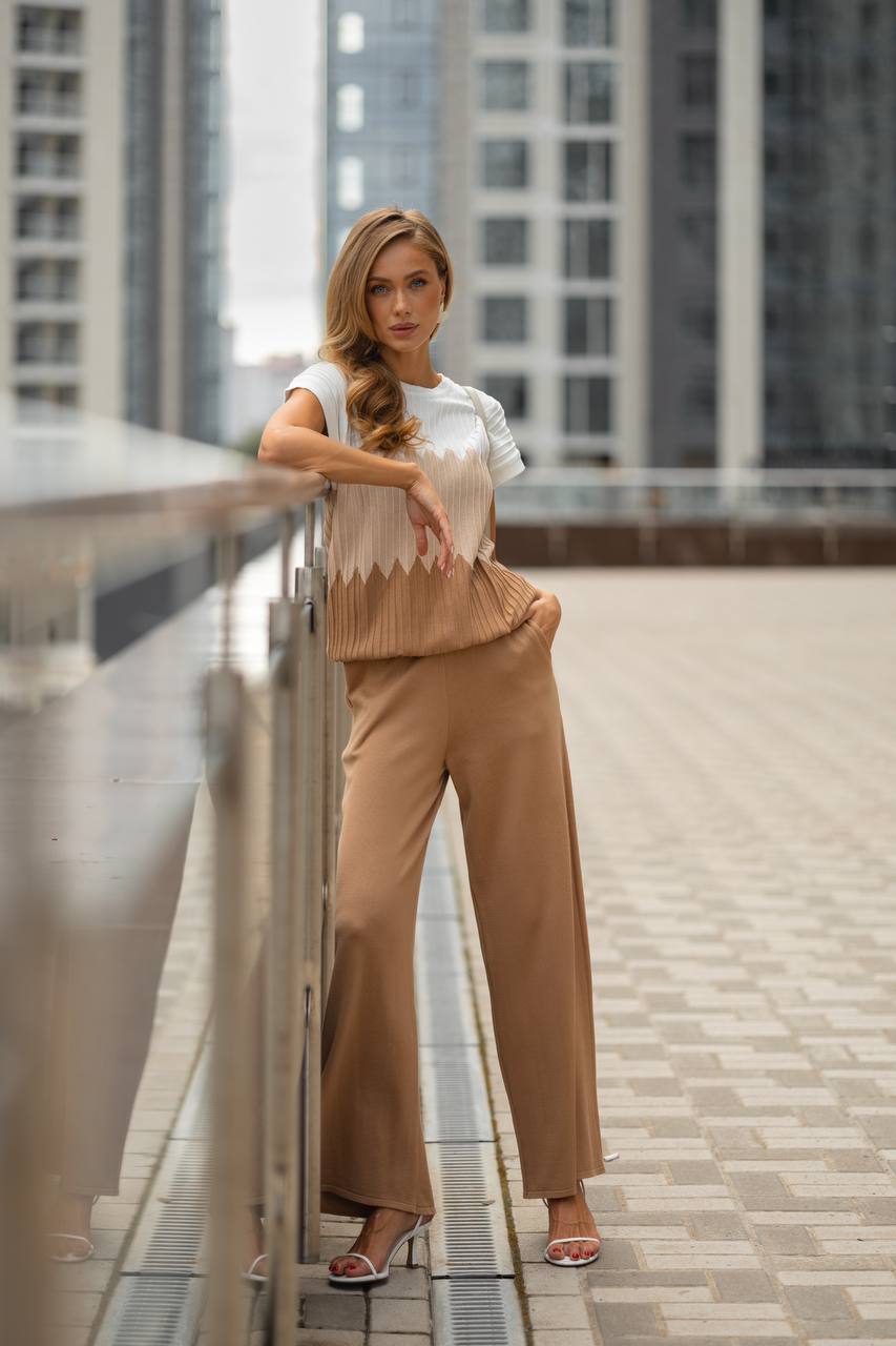 Woman in beige outfit standing on a rooftop with cityscape background