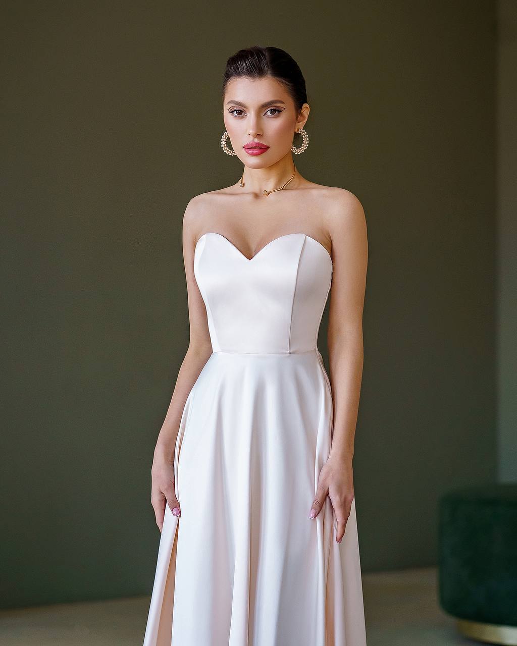 Woman wearing a strapless white dress against a dark background