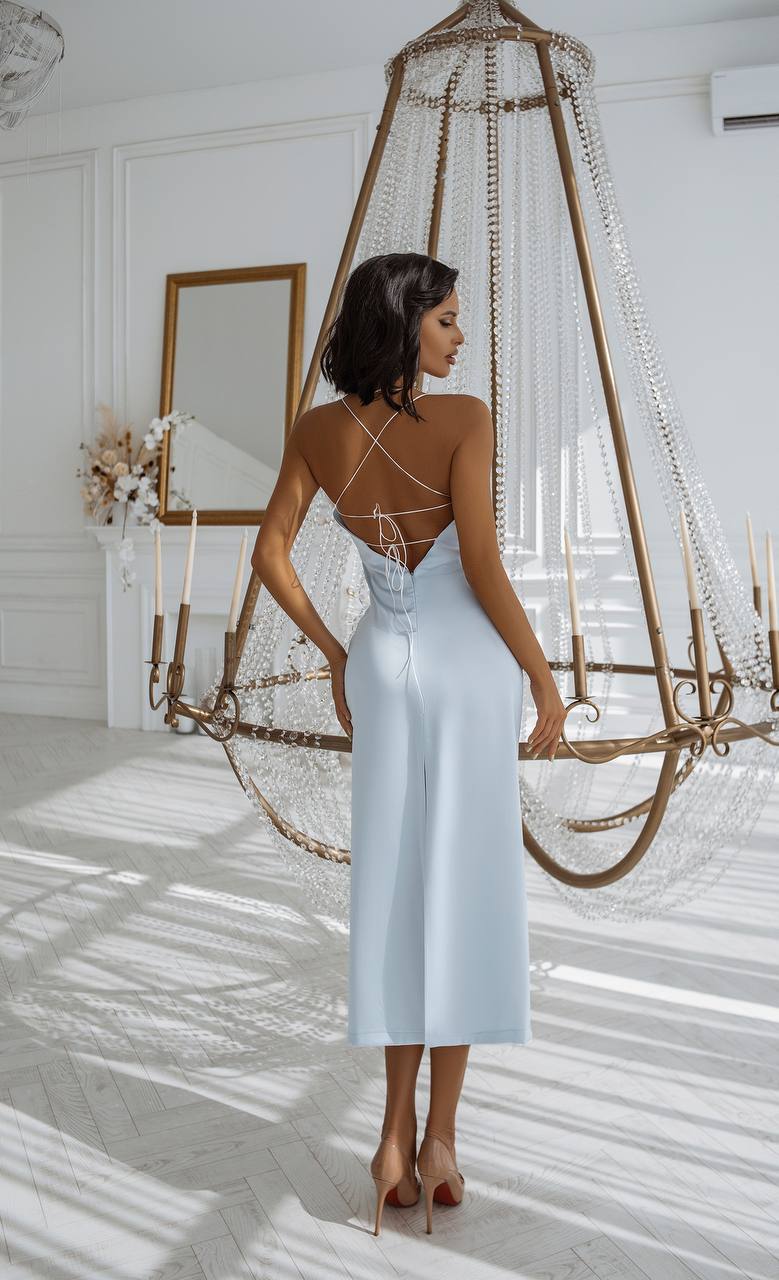 Woman in a light blue dress standing in a room with a decorative hanging structure.