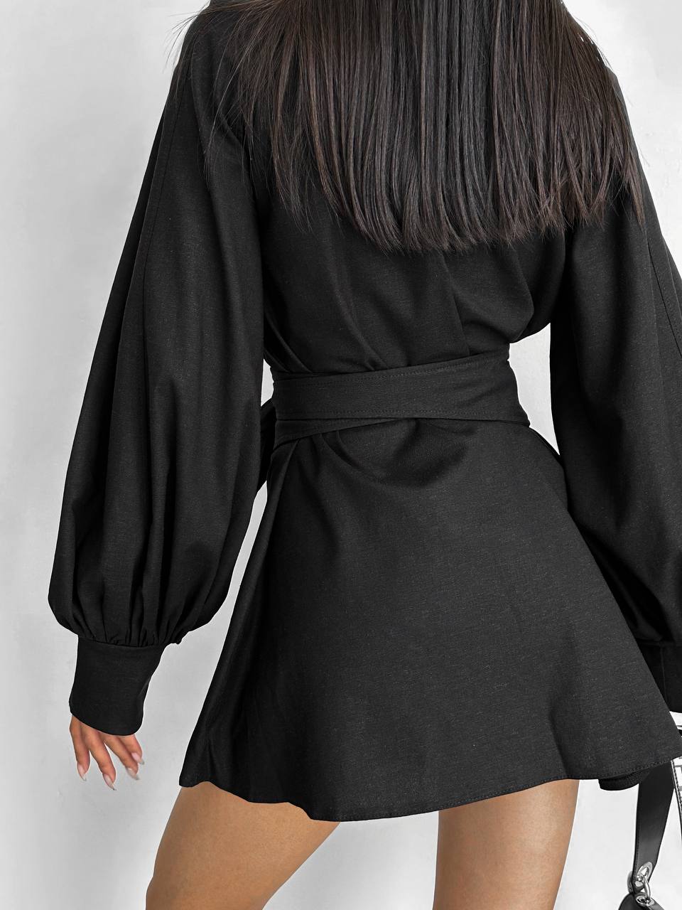 Black dress with long sleeves and a belt on a white background