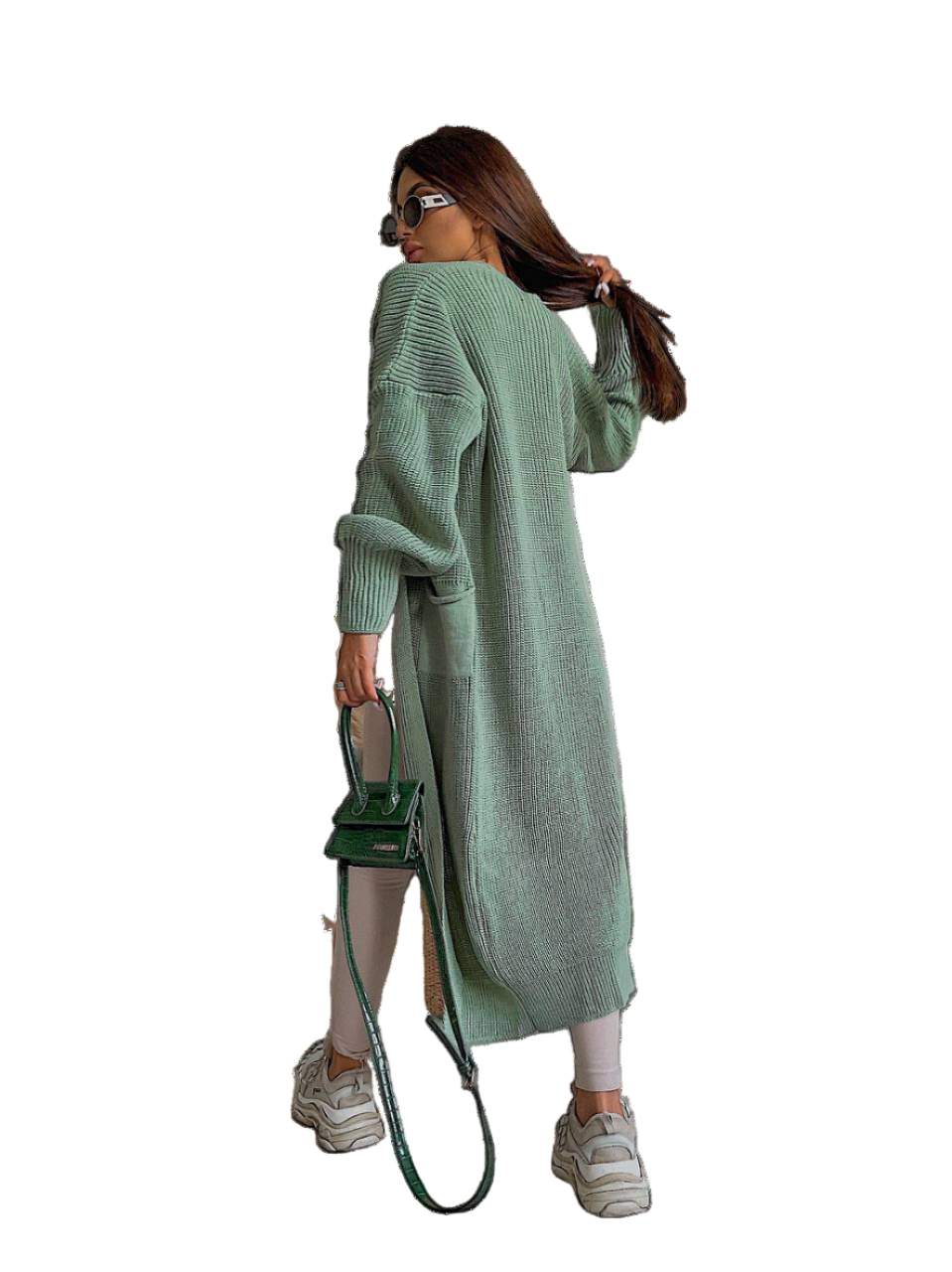 Woman wearing a long green cardigan holding a green handbag on a white background