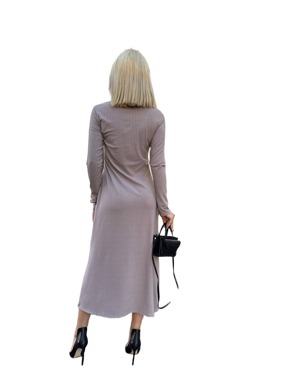 Woman wearing a long-sleeve ribbed dress holding a black handbag on a white background