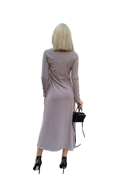 Woman wearing a long-sleeve ribbed dress holding a black handbag on a white background