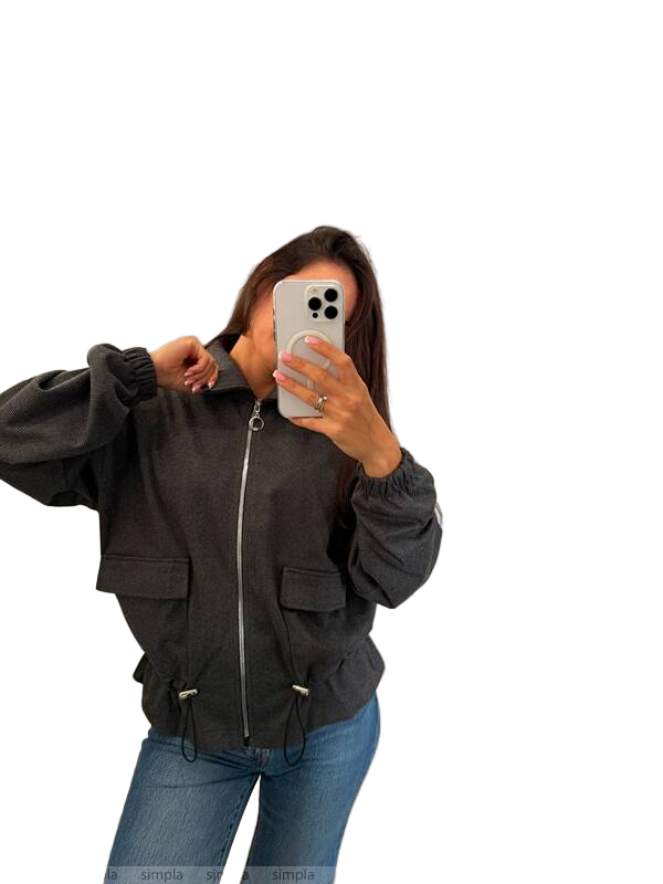Person wearing a black jacket and blue jeans taking a mirror selfie on a white background