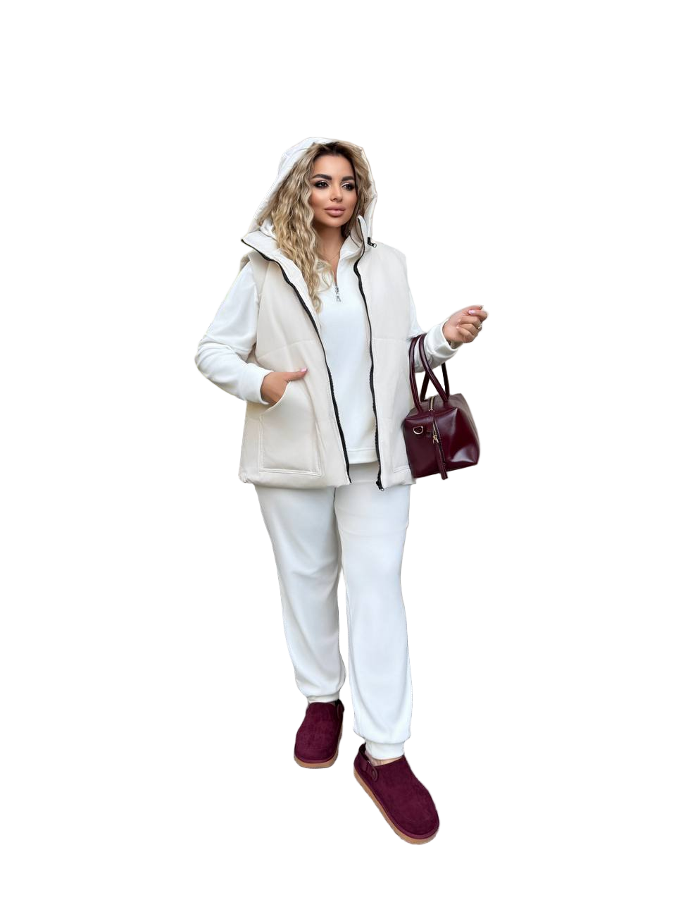 Woman wearing a beige and white outfit with burgundy shoes and handbag on a white background