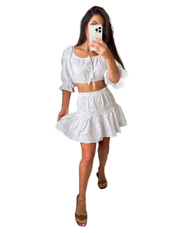 Woman taking a mirror selfie wearing a white outfit on a white background