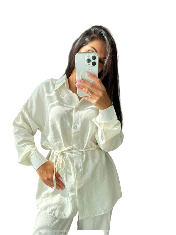 Person wearing a white shirt with a tie waist, taking a mirror selfie.