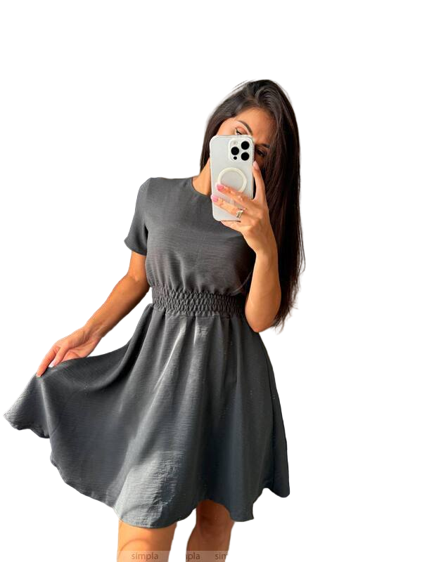 Woman wearing a gray dress taking a mirror selfie on a white background