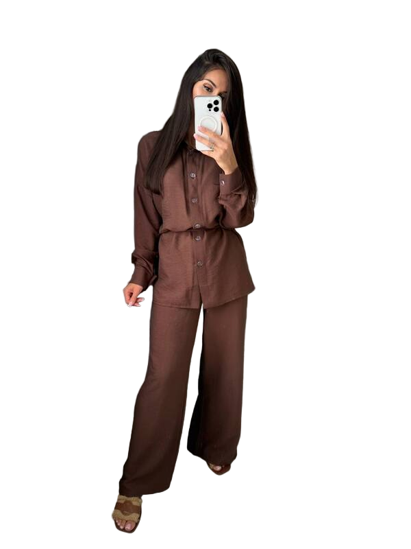 Person wearing a brown outfit holding a phone on a white background