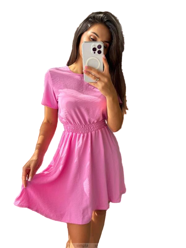 Woman wearing a pink dress with a beige handbag on a white background