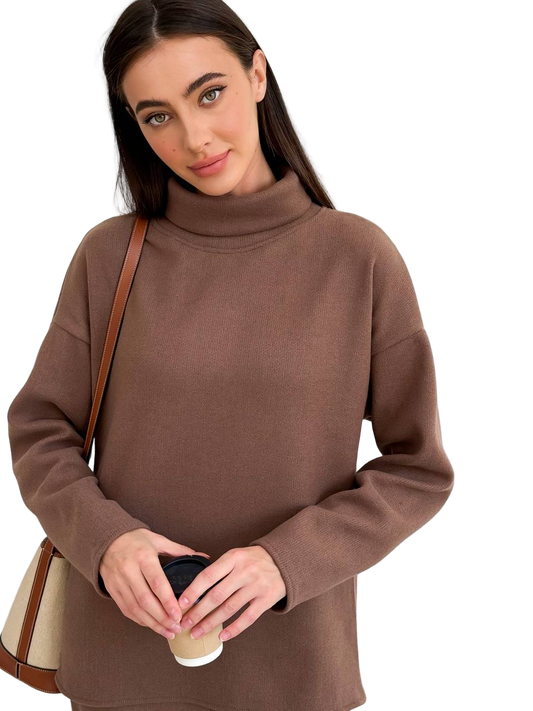 Woman wearing a brown turtleneck sweater holding a coffee cup on a white background