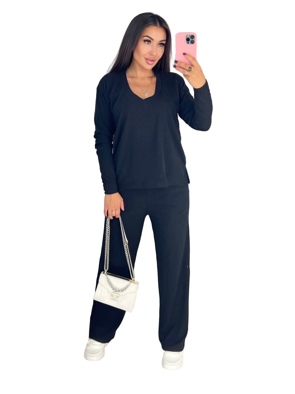 Woman taking a selfie wearing a dark blue outfit with a white handbag on a white background