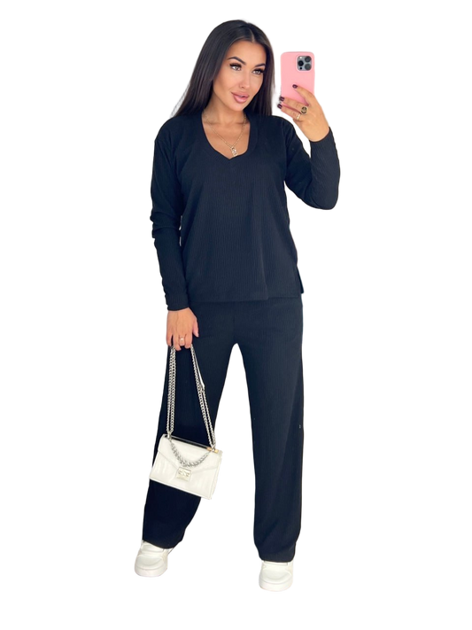 Woman taking a selfie wearing a dark blue outfit with a white handbag on a white background