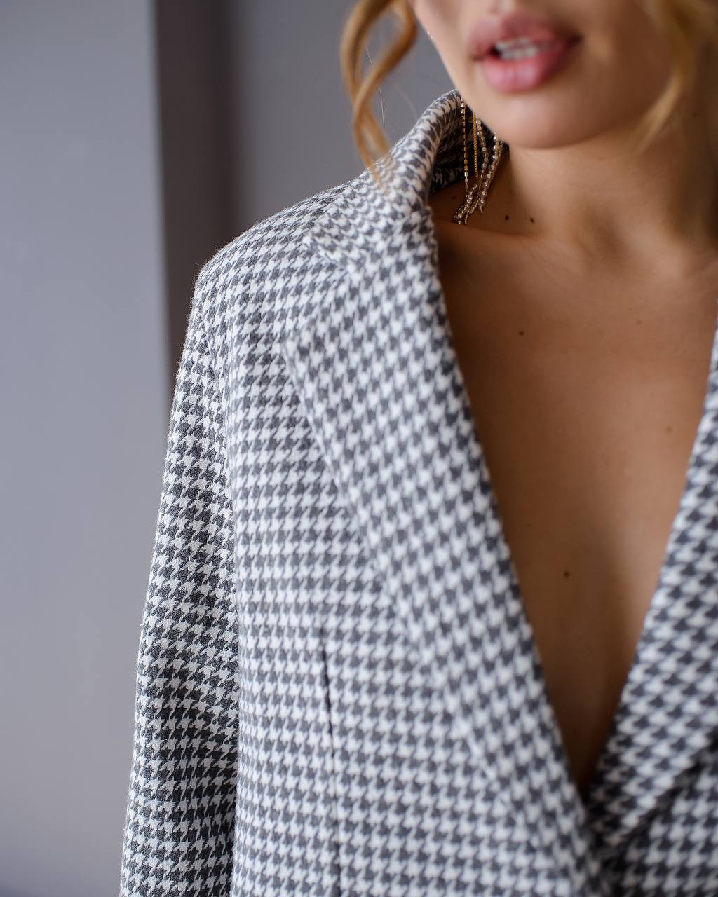 Person wearing a houndstooth patterned blazer with a blurred background