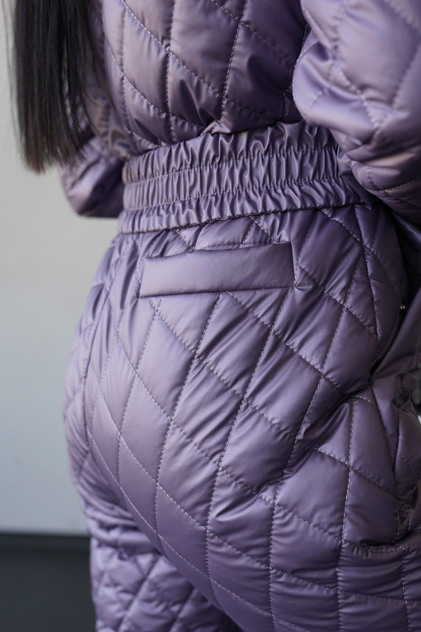 Close-up of a person wearing a quilted purple jacket and pants.