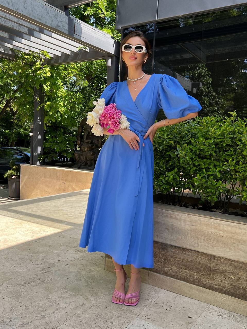 Woman in a blue dress holding flowers outdoors