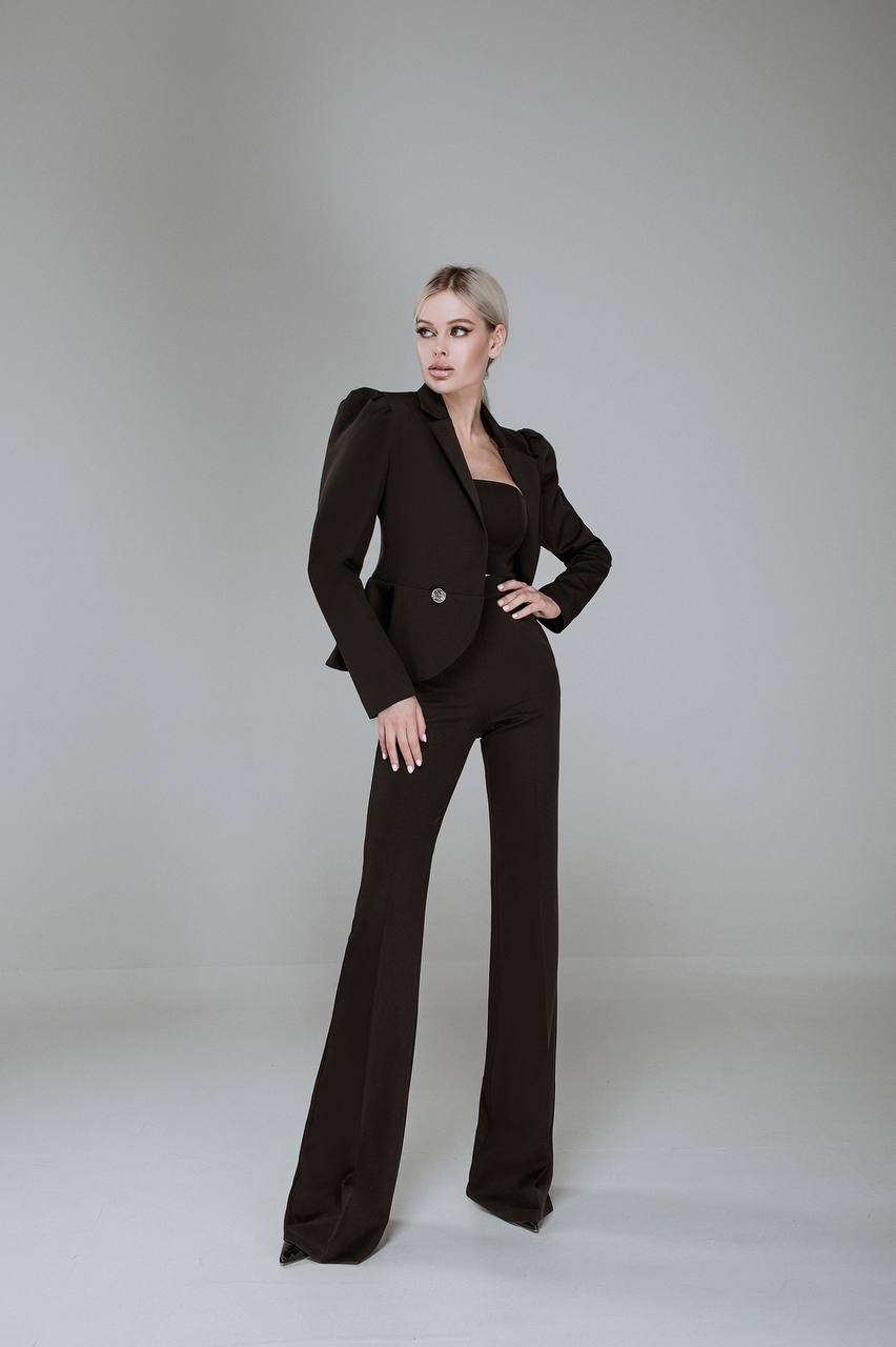 Woman wearing a brown suit standing against a plain background
