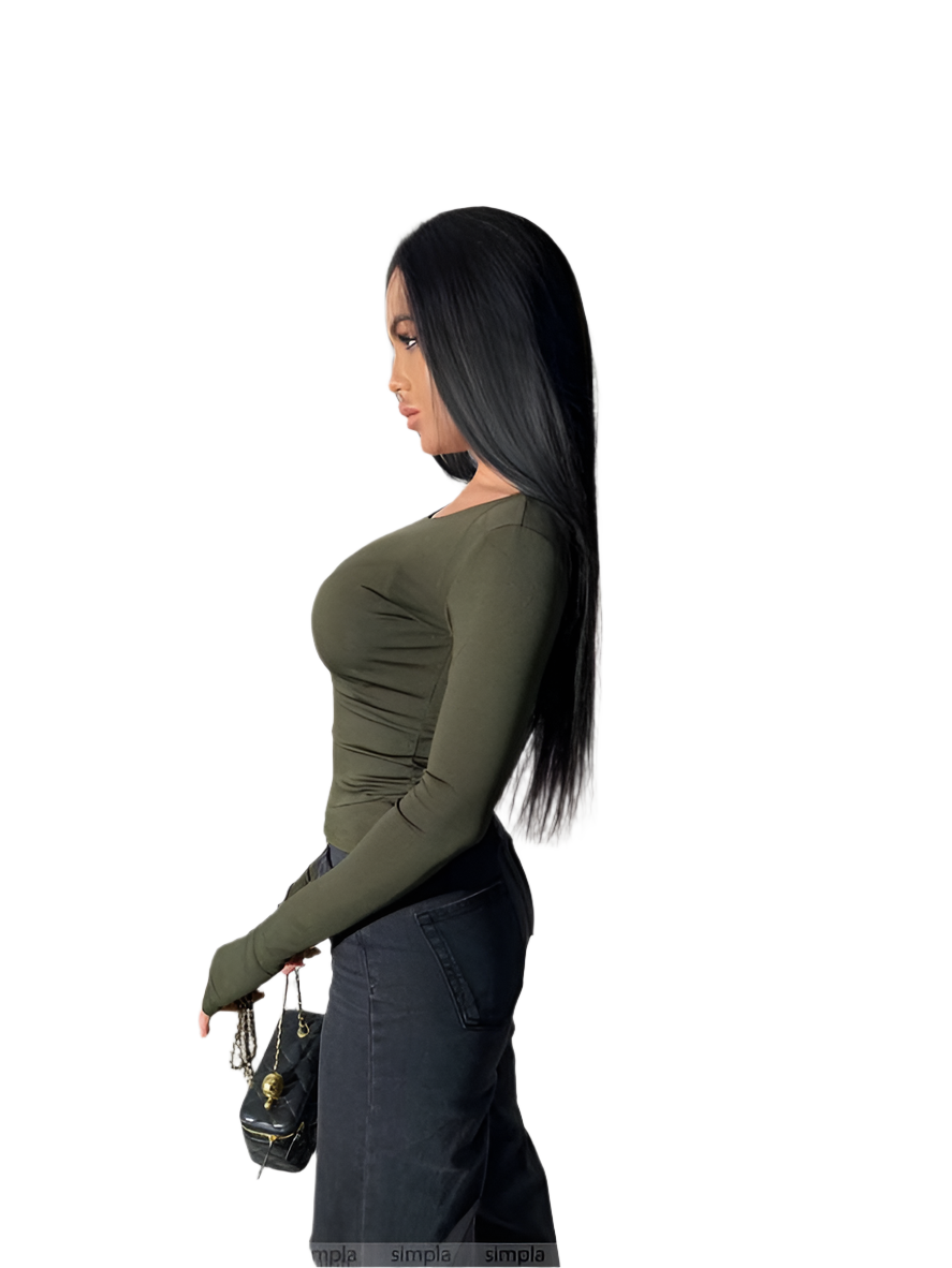 Woman wearing a green long-sleeve top and dark pants on a white background