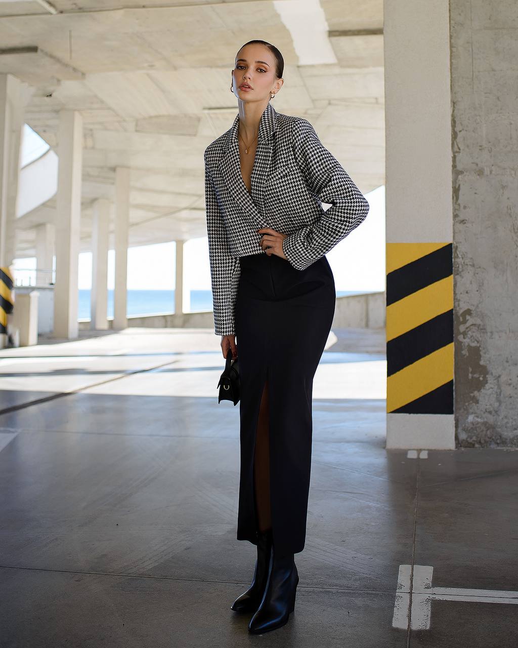 Woman in a checkered shirt and black skirt standing in an industrial setting.