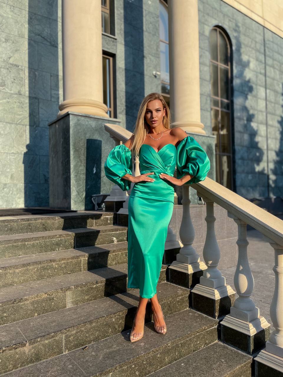 Woman in a green dress standing on steps in front of a classical building