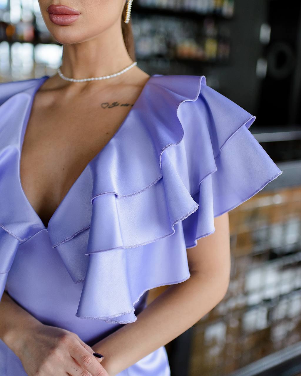 Woman wearing a light purple dress with ruffled layers in an indoor setting.
