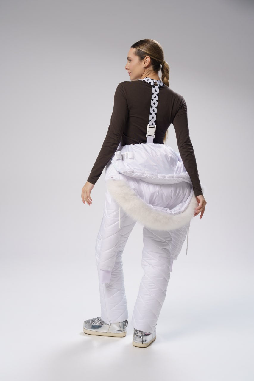 Person wearing a white outfit with suspenders on a gray background