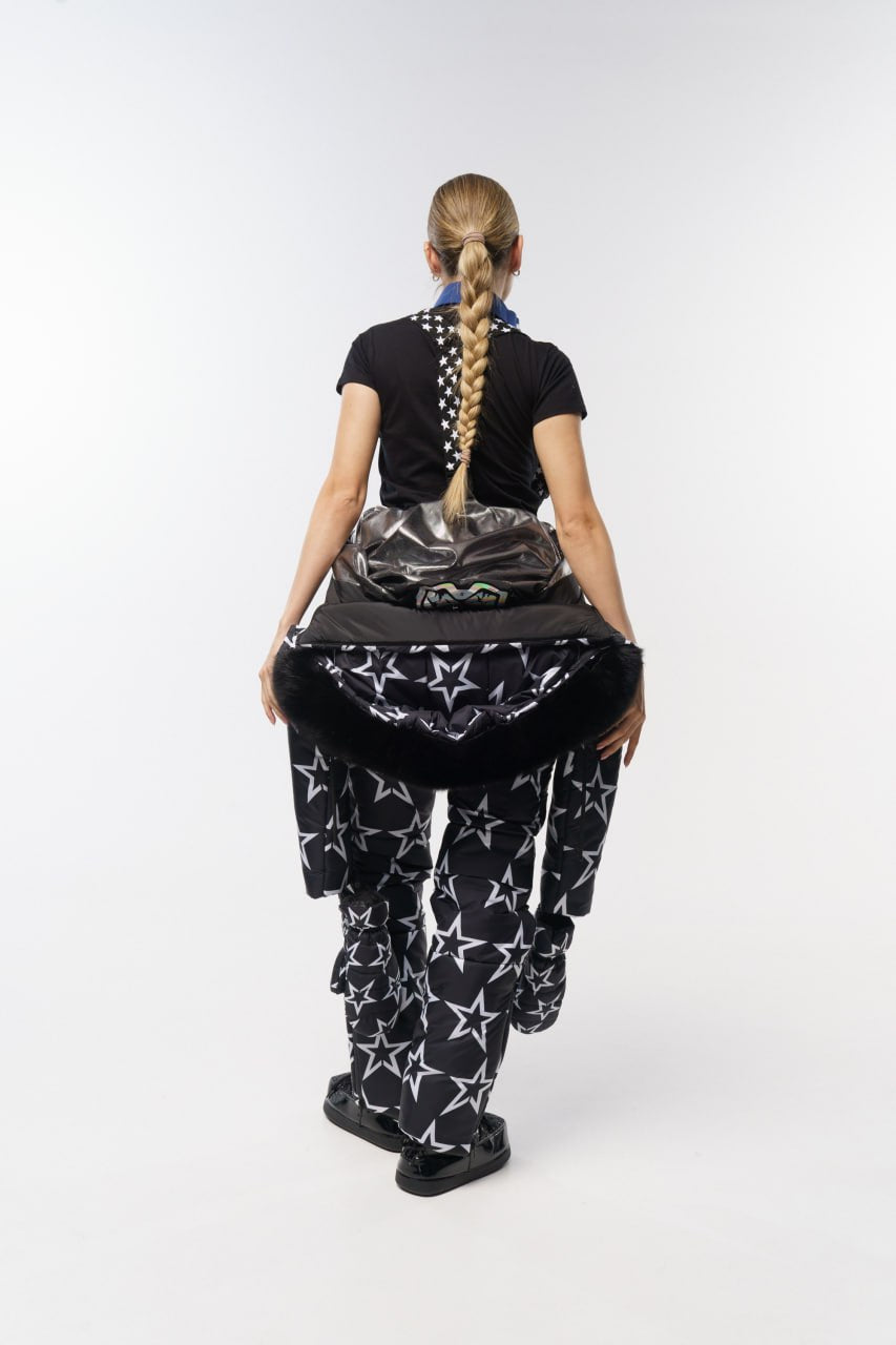 Person wearing a black t-shirt and patterned pants on a white background